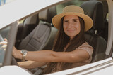 Summer portrait of a girl in a straw hat in a white car.