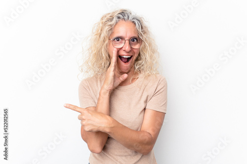 Middle age caucasian woman isolated on white background saying a gossip, pointing to side reporting something.