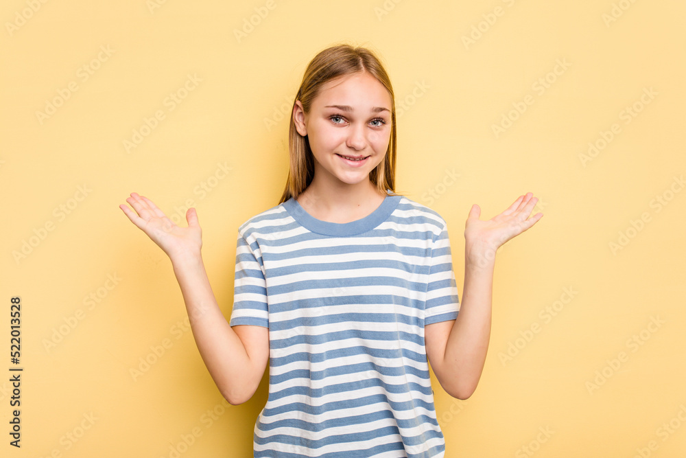Young caucasian girl isolated on yellow background makes scale with arms, feels happy and confident. Young caucasian girl isolated on yellow background makes scale with arms, feels happy and confident.