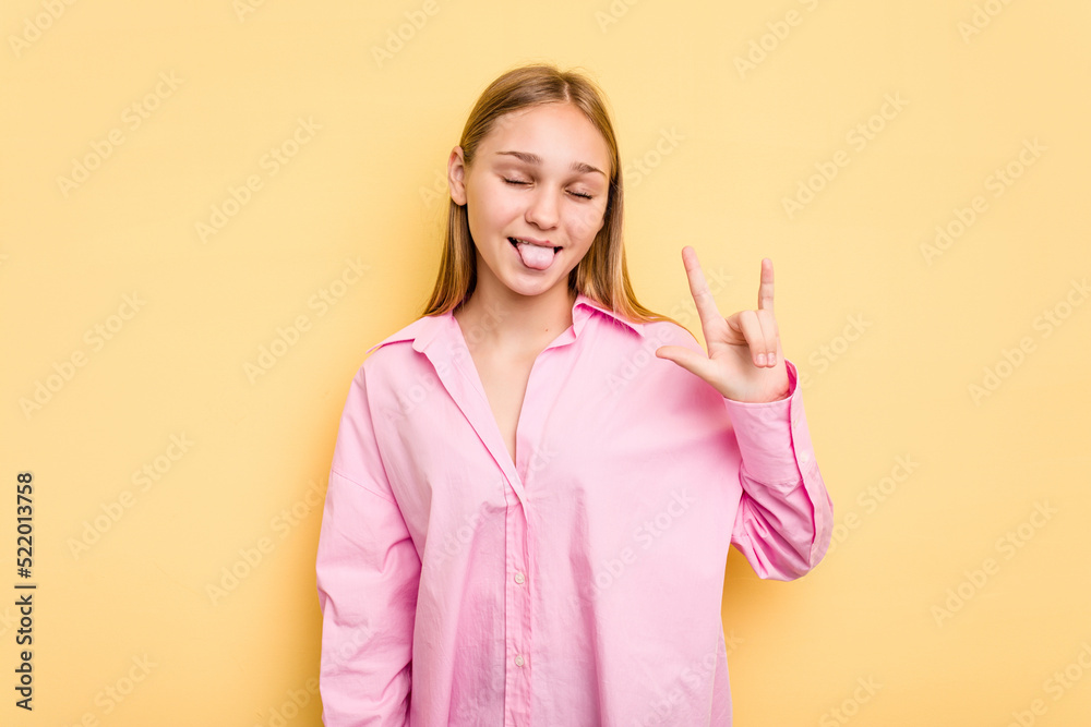 Young caucasian girl isolated on yellow background showing rock gesture with fingers Young caucasian girl isolated on yellow background showing rock gesture with fingers