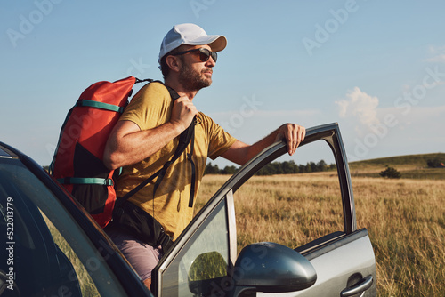 Man camping and hiking in nature, unpacking from car outdoors, recreation and hobbies.