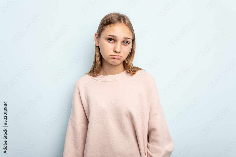Young caucasian girl isolated on blue background sad, serious face, feeling miserable and displeased.