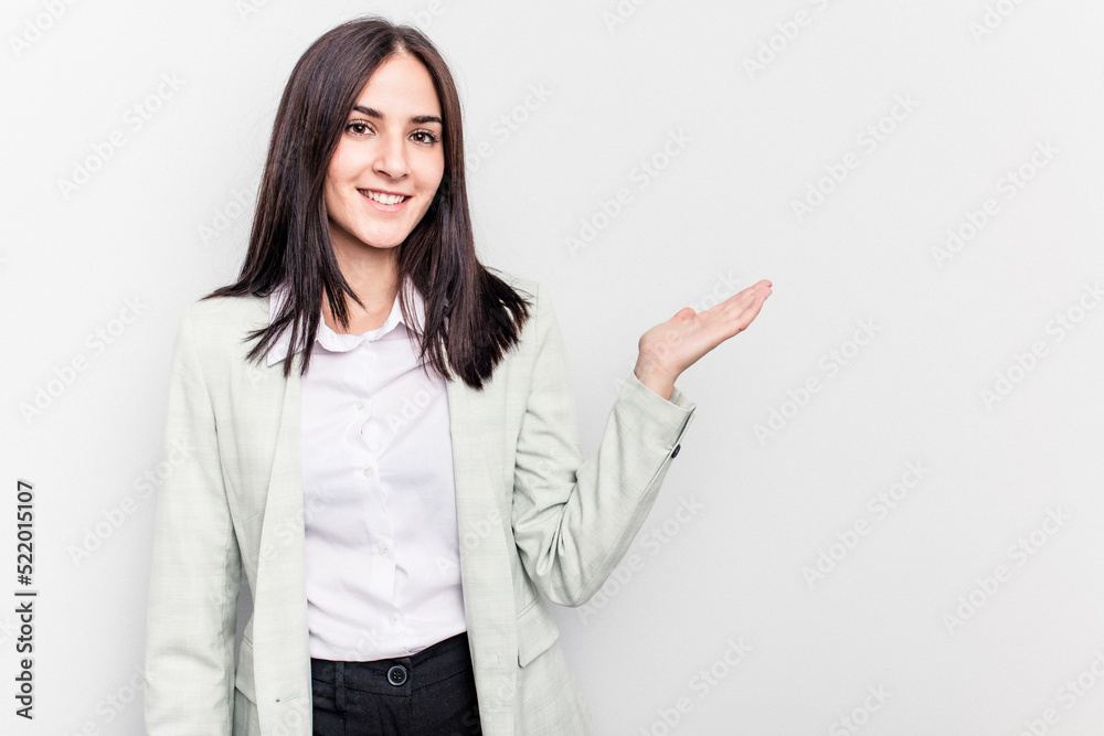 Young business caucasian woman isolated on white background showing a copy space on a palm and holding another hand on waist. Young business caucasian woman isolated on white background showing a copy space on a palm and holding another hand on waist.