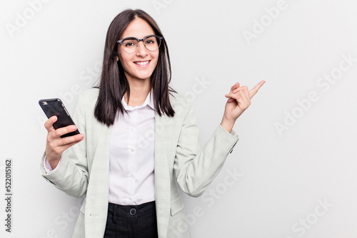 Young business caucasian woman holding mobile phone isolated on white background smiling and pointing aside, showing something at blank space.