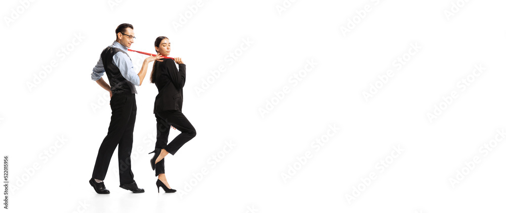 Fototapeta premium Portrait of young woman carrying man, employee on tie isolated on white background. Business control and following