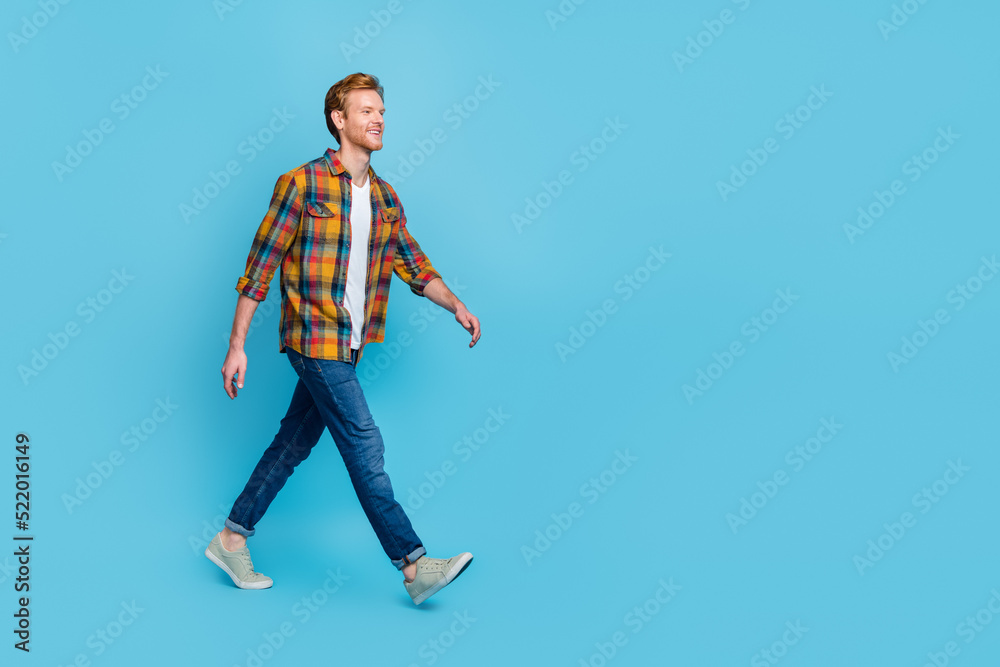 Full length photo of handsome man with ginger hair dressed stylish plaid shirt go shopping big sale isolated on blue color background Full length photo of handsome man with ginger hair dressed stylish plaid shirt go shopping big sale isolated on blue color background