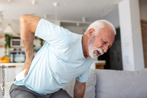 Senior elderly man touching his back, suffering from backpain, sciatica, sedentary lifestyle concept. Spine health problems. Healthcare, insurance