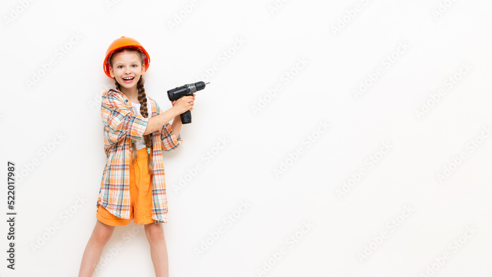 A child with a screwdriver and wearing a construction safety helmet on a white isolated background looks and shows your advertisement. The concept of renovation in the children's room. A child with a screwdriver and wearing a construction safety helmet on a white isolated background looks and shows your advertisement. The concept of renovation in the children's room.