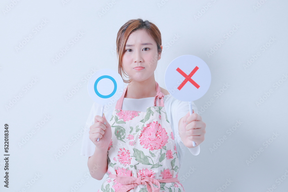 ✖️の札を突き出すエプロン姿の女性 ✖️の札を突き出すエプロン姿の女性