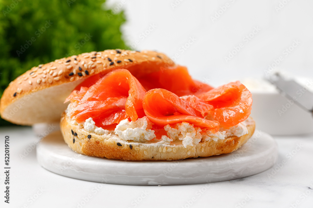 Bagel sandwich with salmon and cream cheese on marble board and white background Bagel sandwich with salmon and cream cheese on marble board and white background