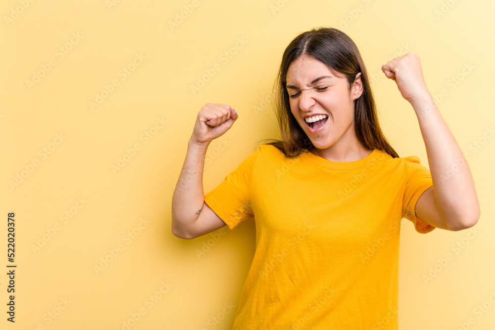 Young caucasian woman isolated on yellow background raising fist after a victory, winner concept. Young caucasian woman isolated on yellow background raising fist after a victory, winner concept.