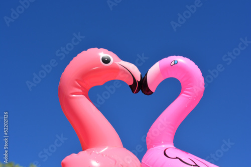 Pink flamingoes love heart shape against blue sky