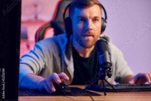 Playing the game. Man in headphones and with microphone is live on the stream