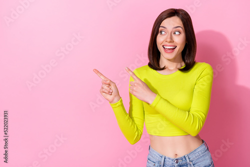 Photo of funny dreamy girl dressed lime shirt looking pointing two fingers empty space isolated pink color background