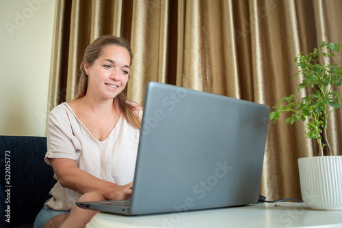 Mujer tarbajando desde casa con su laptop, con actitud positiva, tranquila y feliz	 photo