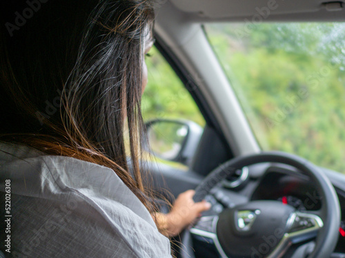 indian young woman driving a car suv in the mountain road a rainy cloudy day photo