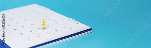Yellow pin on event calendar. Planner calendar on blue background, plan for business meetings. 