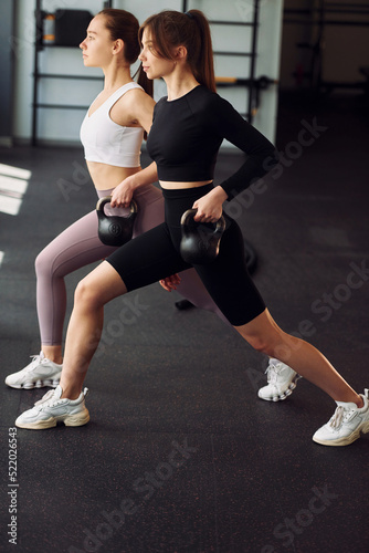 Lifting the weights. Two women in sportive clothes have fitness day in the gym together