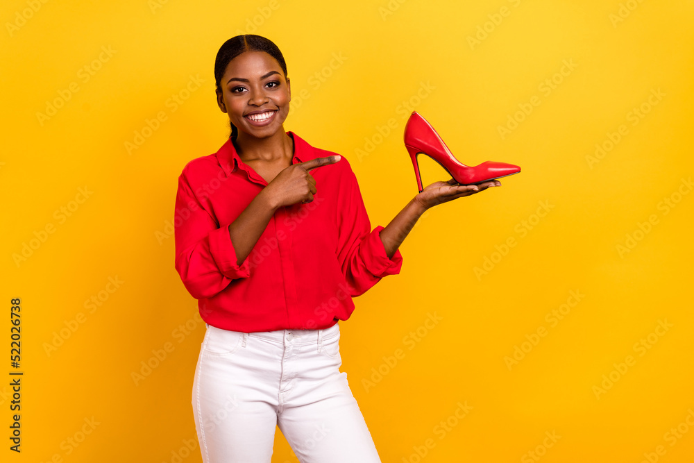 Photo of young pretty girl indicate finger shoes select suggest proposition isolated over yellow color background Photo of young pretty girl indicate finger shoes select suggest proposition isolated over yellow color background
