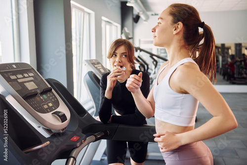 Cardio exercises. Running on the racetrack. Two women in sportive clothes have fitness day in the gym together