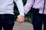 Young couple in love holding hands in the park. Close up picture of girlfriend and boyfriend, standing walking in the street. Romantic relationship in teenage time. Sex education for children.