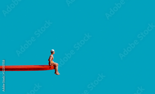 miniature man sits on the edge of a diving board photo