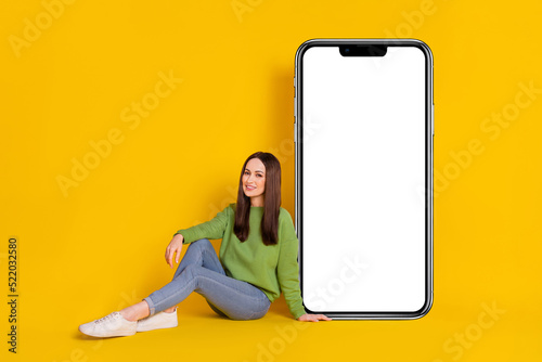 Portrait of attractive cheery woman sitting on floor door copy empty blank space isolated on bright yellow color background
