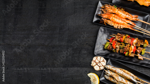 Various barbecue delicacies are placed on the black wood background
