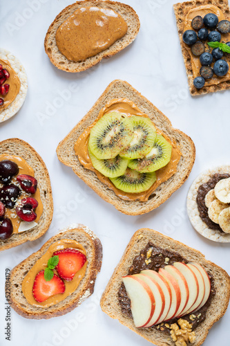 Various kind of open sandwiches with berries and fruits. Made from bread  such as wholegrain  rice crakers  crispbreads and different nut butter  such as peanut  crunchy cashew and almond butter