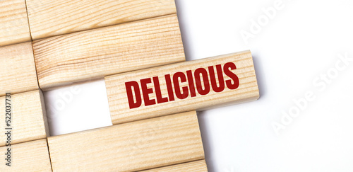On a light background, wooden blocks with the text DELICIOUS. Close-up top view. photo