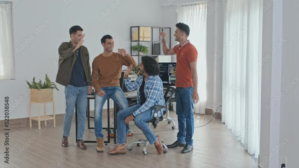 Slowmo portrait of team of joyful male Indian programmers giving high fives to each other, smiling and showing thumbs up at camera at modern IT office Slowmo portrait of team of joyful male Indian programmers giving high fives to each other, smiling and showing thumbs up at camera at modern IT office