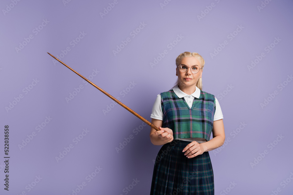 Blonde student in eyeglasses holding pointer on purple background Blonde student in eyeglasses holding pointer on purple background