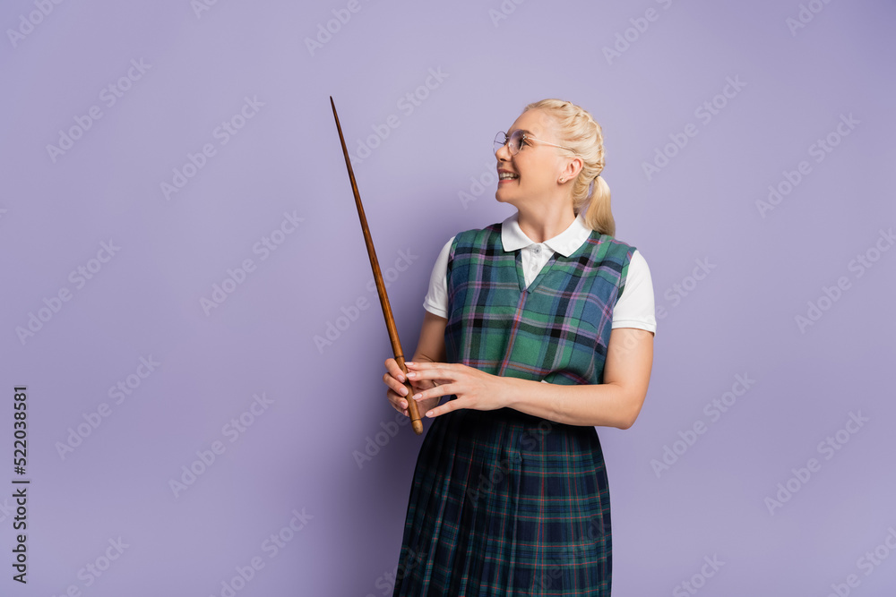 Positive student in vest looking at pointer on purple background Positive student in vest looking at pointer on purple background