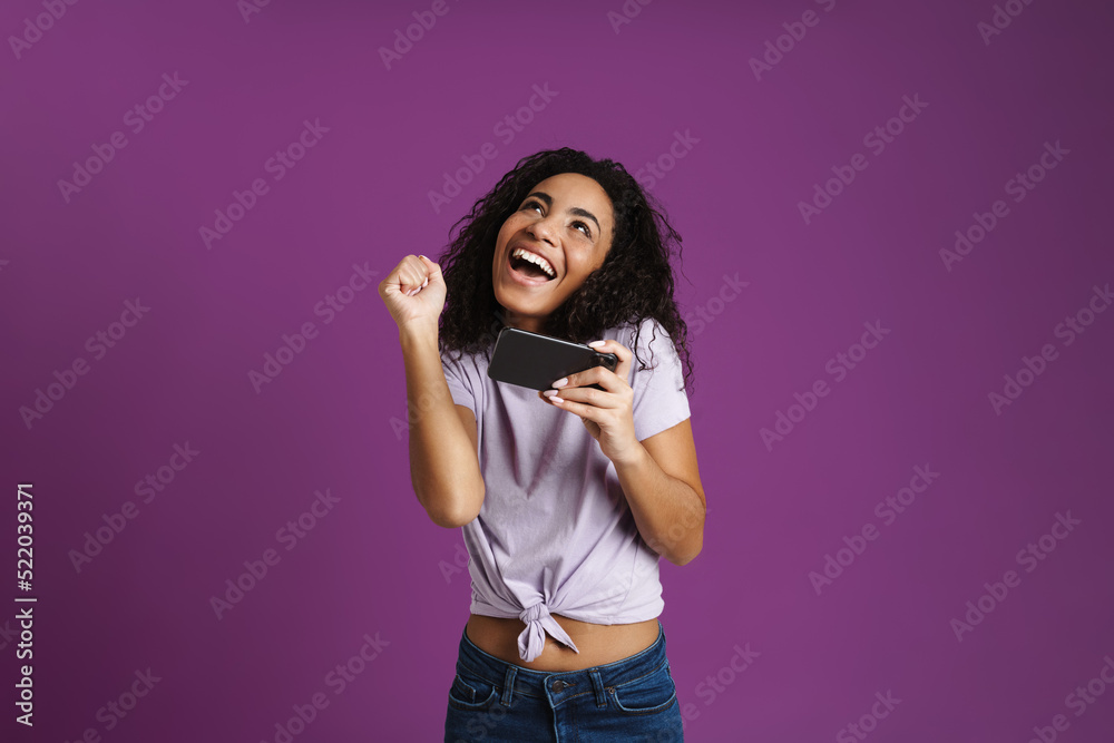Fototapeta premium Young black woman gesturing while playing online game on cellphone