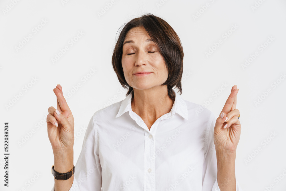 Mature brunette woman smiling while holding fingers crossed Mature brunette woman smiling while holding fingers crossed