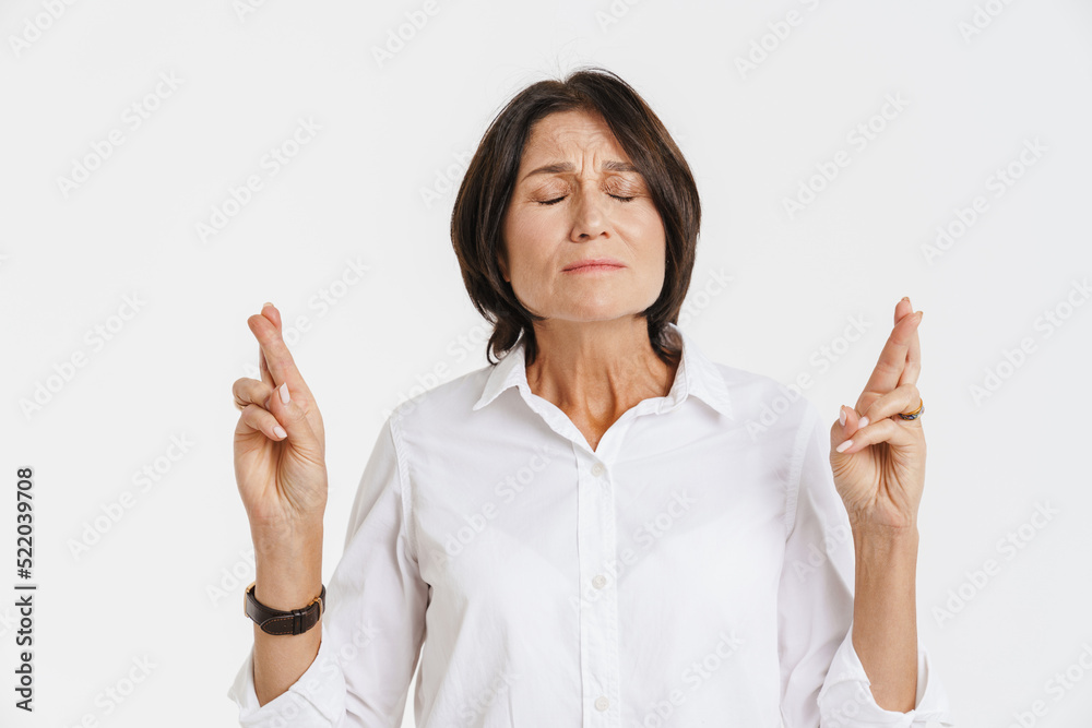 Mature brunette woman frowning while holding fingers crossed Mature brunette woman frowning while holding fingers crossed