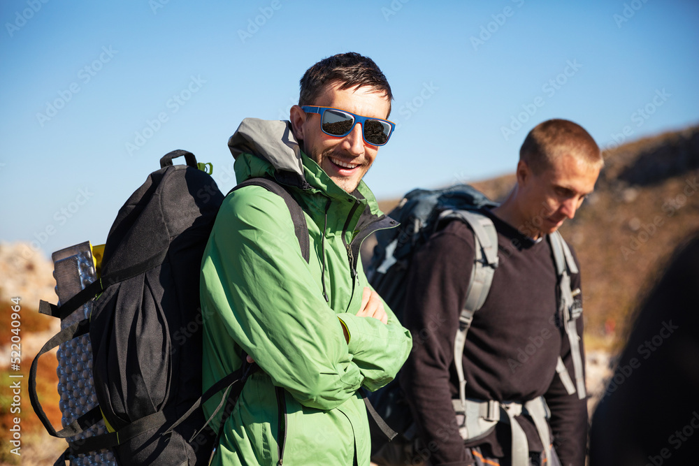 Two men with backpacks hiking in mountainous area. With clipping path - reflection in sunglasses Two men with backpacks hiking in mountainous area. With clipping path - reflection in sunglasses