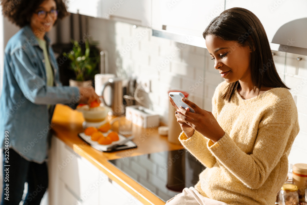 Black girl using mobile phone during spending time with her mother Black girl using mobile phone during spending time with her mother