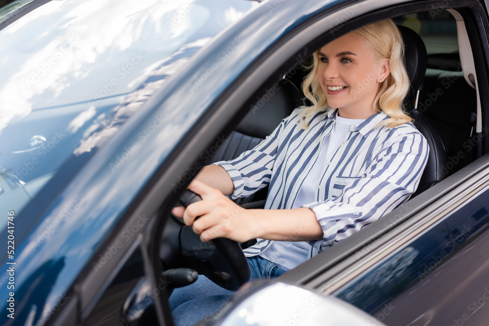 Positive woman sitting in car during driving courses