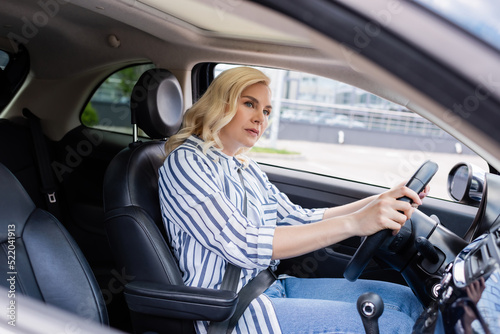 Blonde driver looking away while driving car during course in car