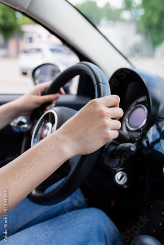 Cropped view of woman holding reeling wheel in car