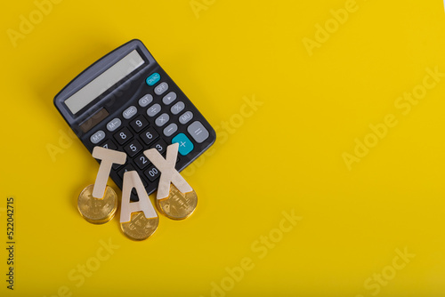 Tax BTC cryptocurrency with TAX wording and calculator on yellow background photo