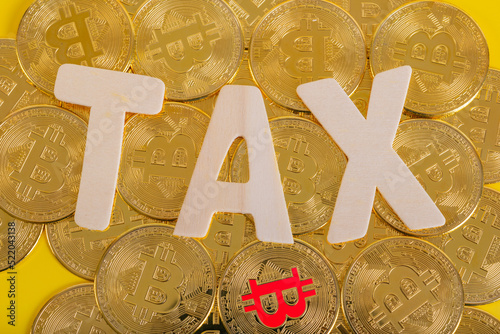 Tax BTC cryptocurrency with TAX wood wording on bitcoin with yellow background