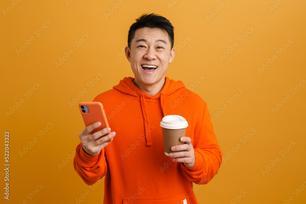 Asian young man drinking coffee while using mobile phone Asian young man drinking coffee while using mobile phone