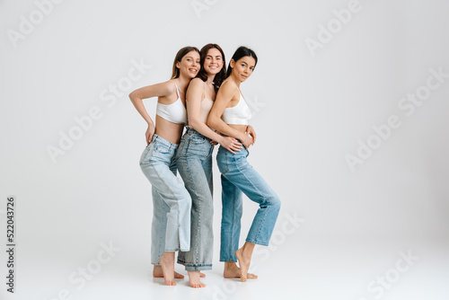 Full lenght portrait of three young beautiful ladies standing isolated