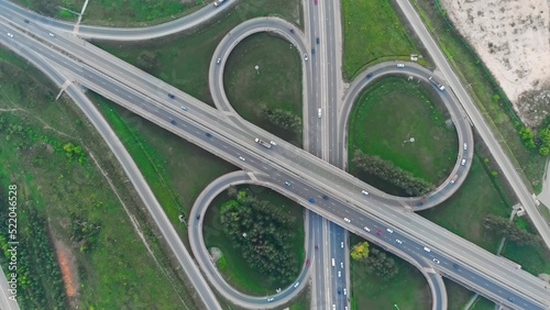 Top view of the highway with many interchanges in different directions with a large number of cars that move one after another and change lanes to the desired exit from the highway.