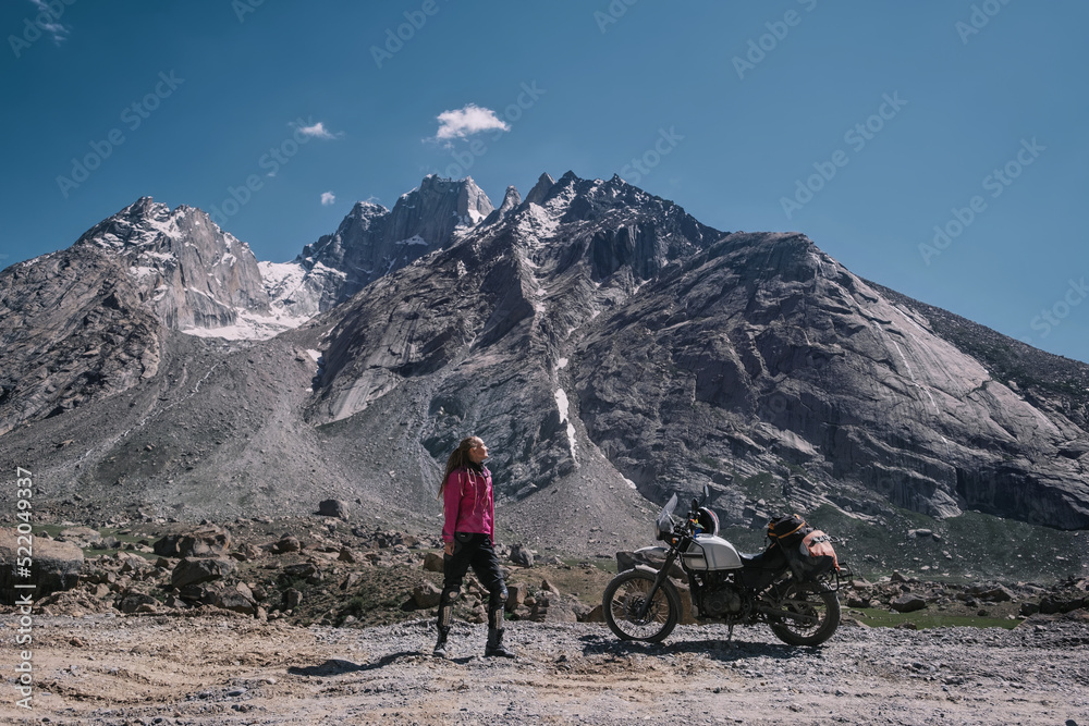 Woman biker in dangerous moto trip in the mountains with off-road motorcycle stunning high mountain background