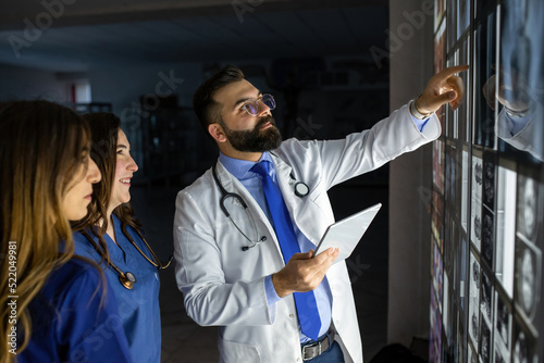 A group of surgeon interns is studying fetal development at different stages of pregnancy. Health education concept. Medical students in the classroom with images of ultrasound photo