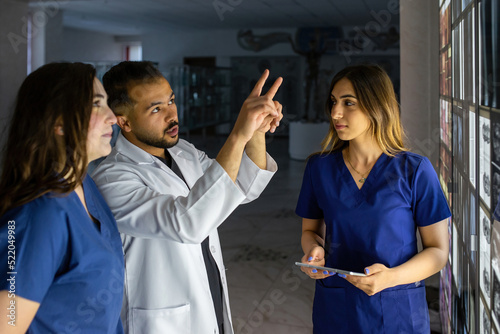 A group of surgeon interns is studying fetal development at different stages of pregnancy. Health education concept. Medical students in the classroom with images of ultrasound