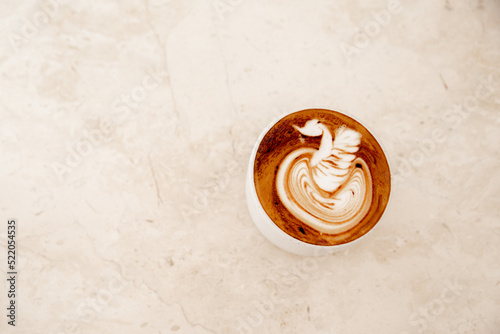 White cup of tasty cappuccino with latte art on white marble background in cafe